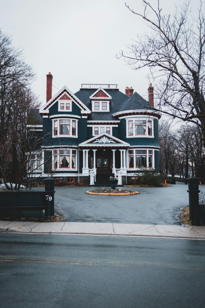 A beautiful Victorian-style house in a suburban neighborhood with overcast skies and tree-lined streets.