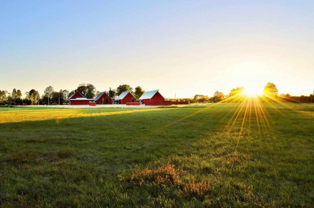 Beautiful sunset over a rural farm in Beachwood with pre engineered metal building and lush fields.