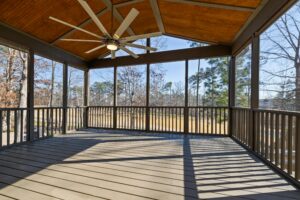 A well-lit patio with a ceiling fan offering a view of nature during the day.